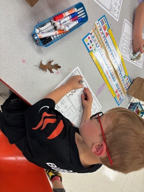Boy with blonde hair and red glasses coloring