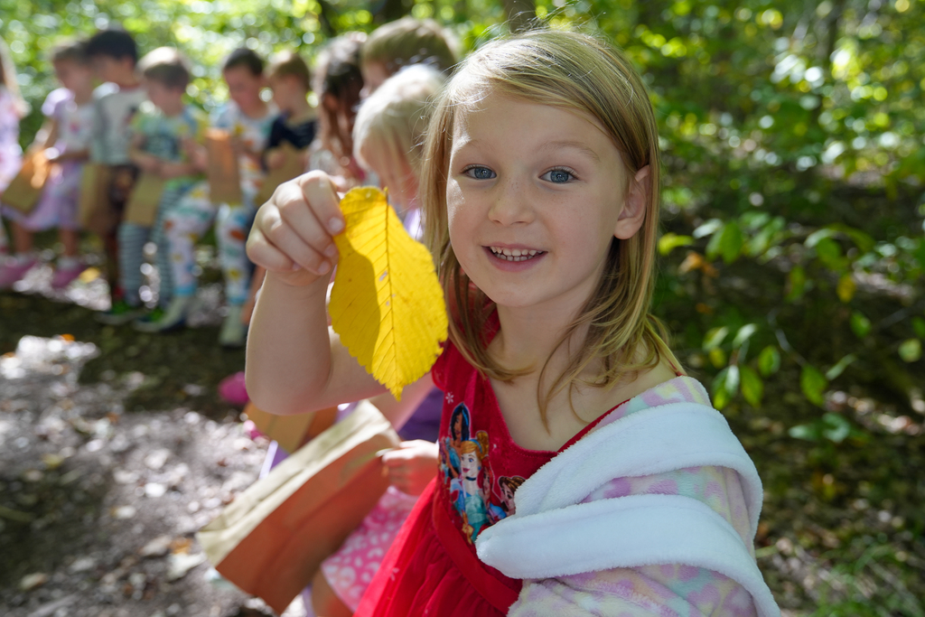 Girl with Blonde hair holding large yellow leaf