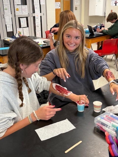 Two girls creating fake wounds