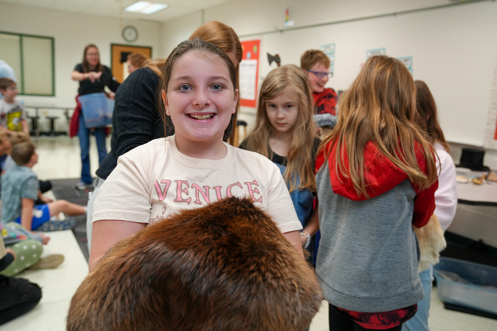 A girl smiling while holding a large fur