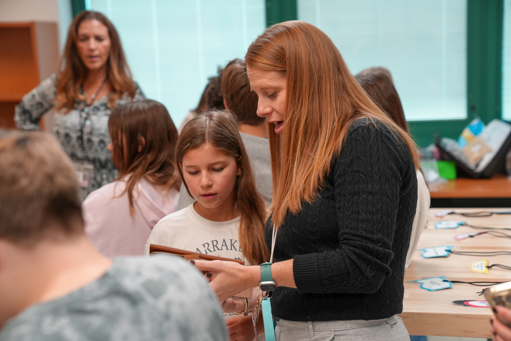 A red headed teacher talking with a young female student