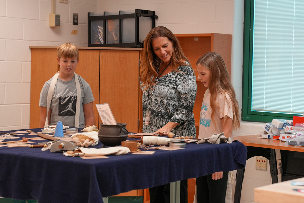 a teacher over a table of relics with two students