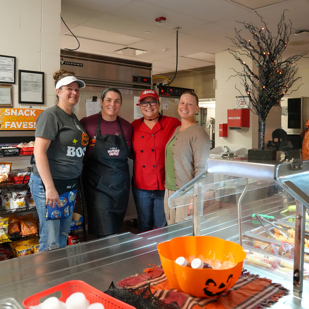 A couple of  ladies smiling at the camera in a cafeteria