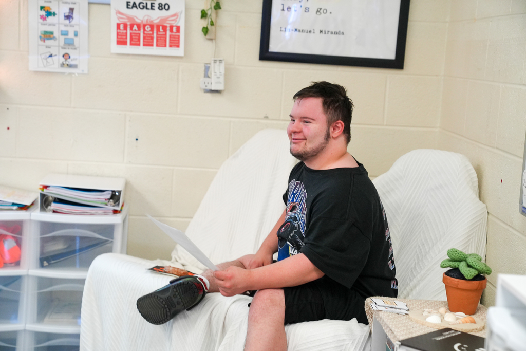 A student with their legs crossed smiling 