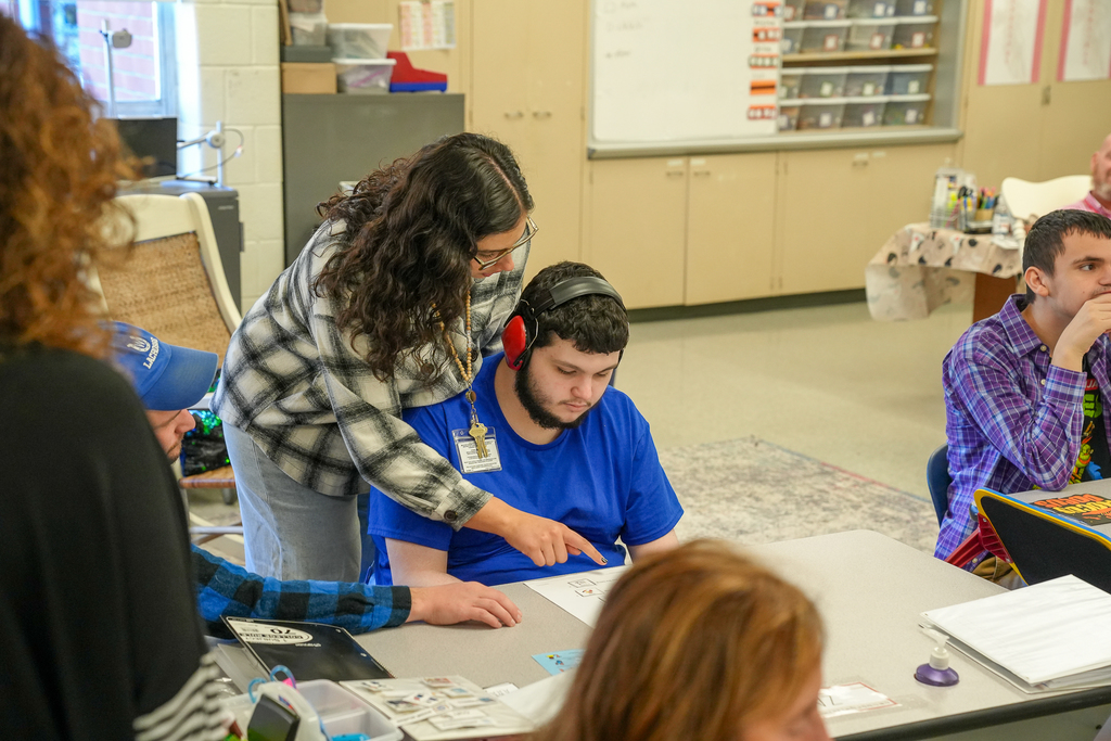 A woman working with a student with headphones on