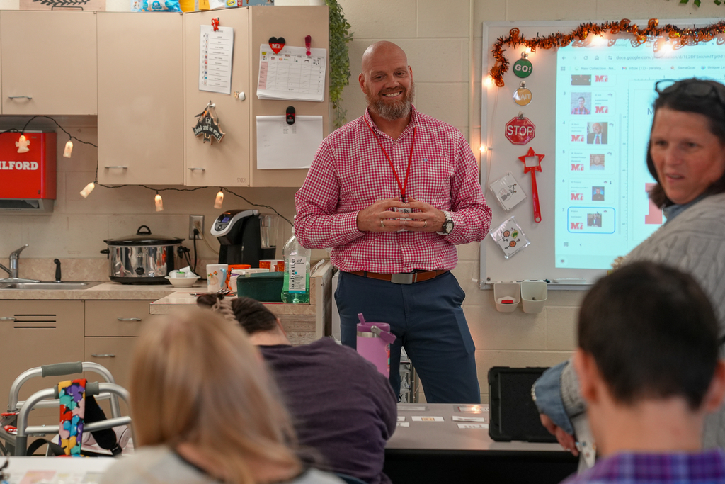 A bald man with a beard smiling at a student 