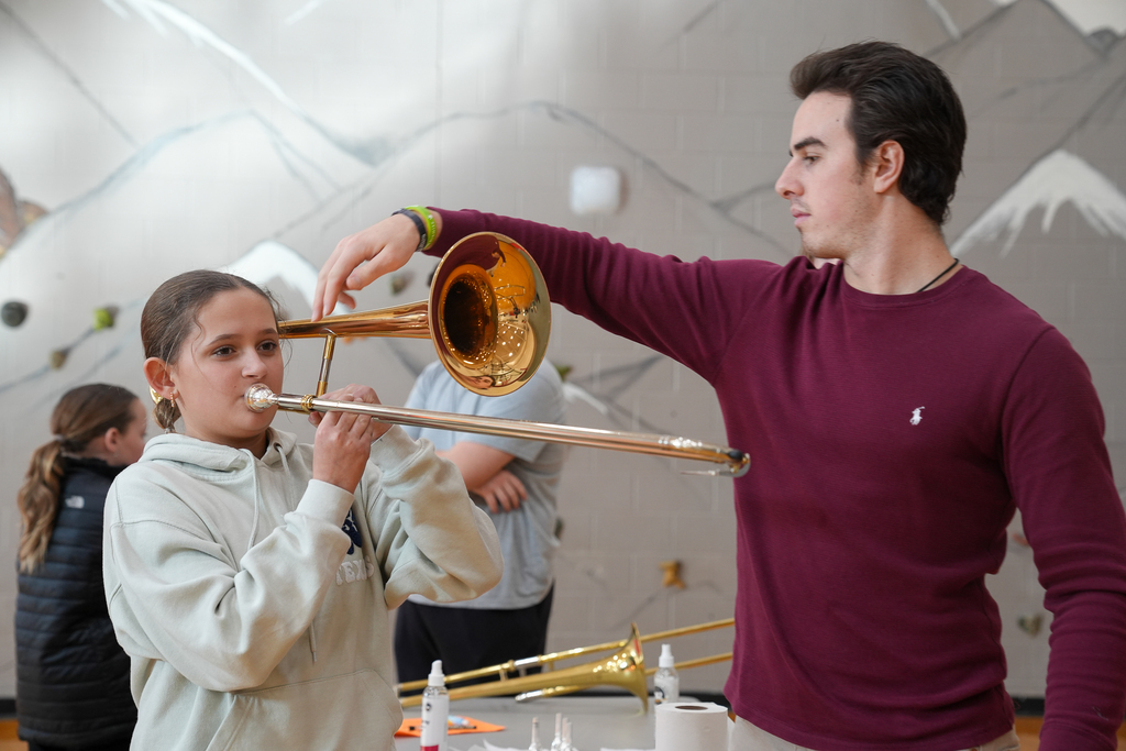 A man helping a girl play trombone