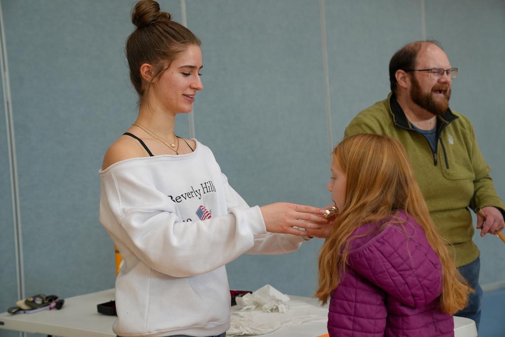 a young girl holding a flute for a lady