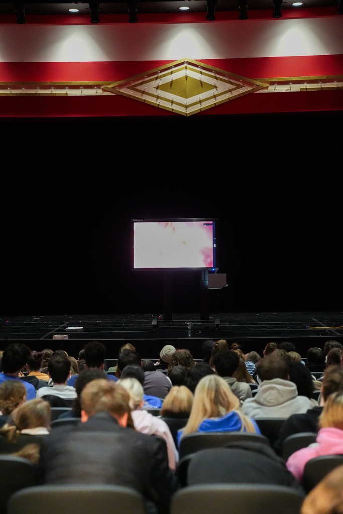Students sit in an auditorium watching a large screen displaying a live surgical broadcast during a special seminar for Honors Anatomy and Physiology and AP Biology classes.