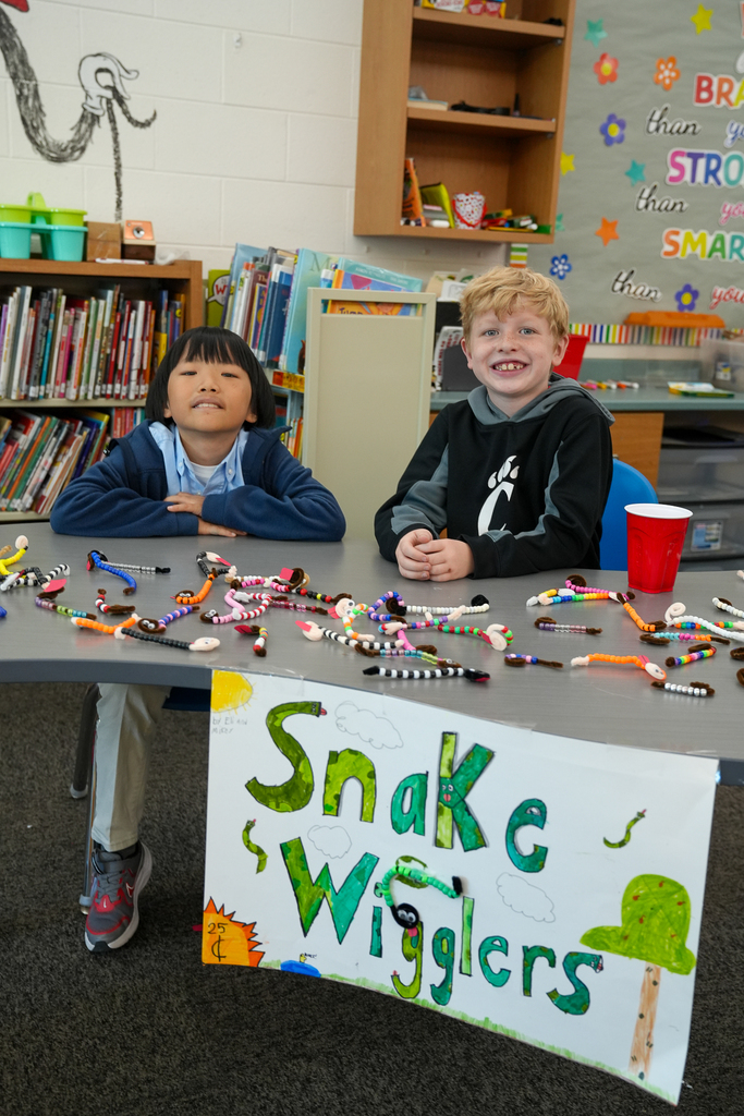 Two students in front of a table selling fuzzy snakes