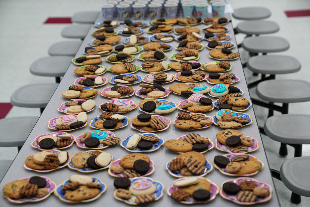 Plates filled with cookies and sweet treats are arranged across cafeteria tables for families attending Mulberry’s “Poet-Tea” celebration.
