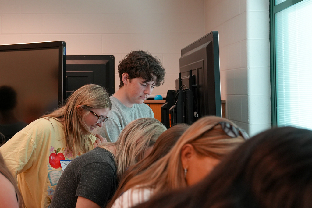 Two graduating seniors stand at a touchscreen display while looking through photos or materials during the Mulberry senior breakfast event.