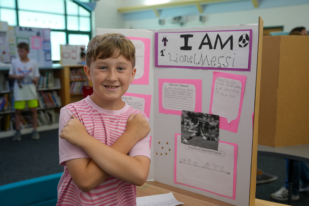 A student smiles while posing beside a Lionel Messi presentation board during the Wax Museum event.