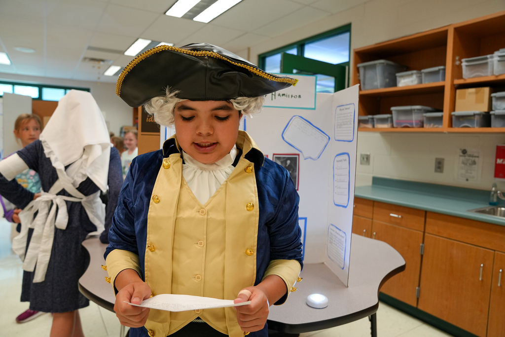 A student dressed as Alexander Hamilton presents information from note cards during the Wax Museum event.