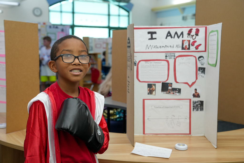 A student dressed as Muhammad Ali poses with boxing gloves in front of his historical figure display during Meadowview Elementary’s Wax Museum.