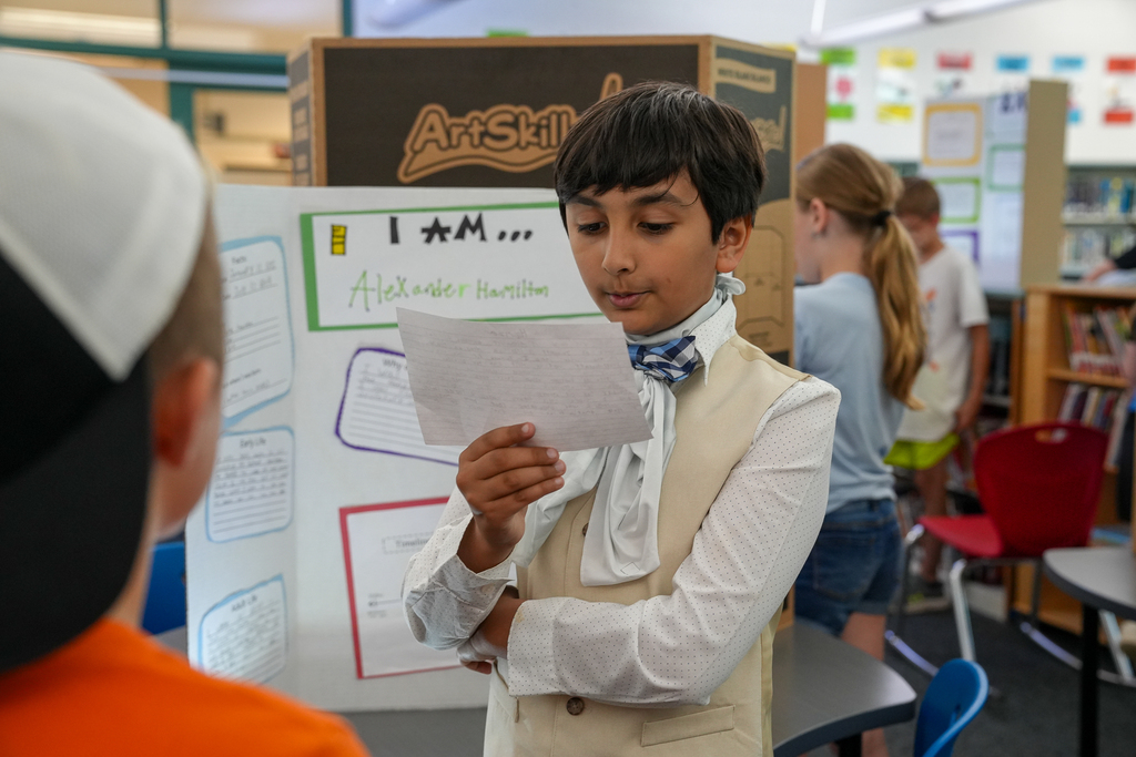 A student dressed as Alexander Hamilton reads from a note card while presenting facts about the historical figure during Meadowview Elementary’s Wax Museum.
