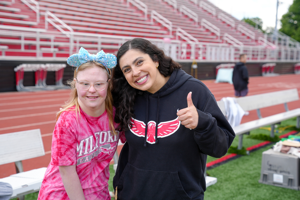 A high school student wearing glasses posing with a teacher wearing a milford hoodie