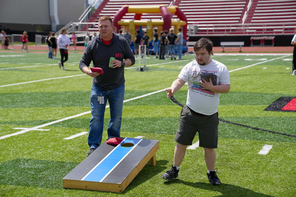 two high school students playing cornhole
