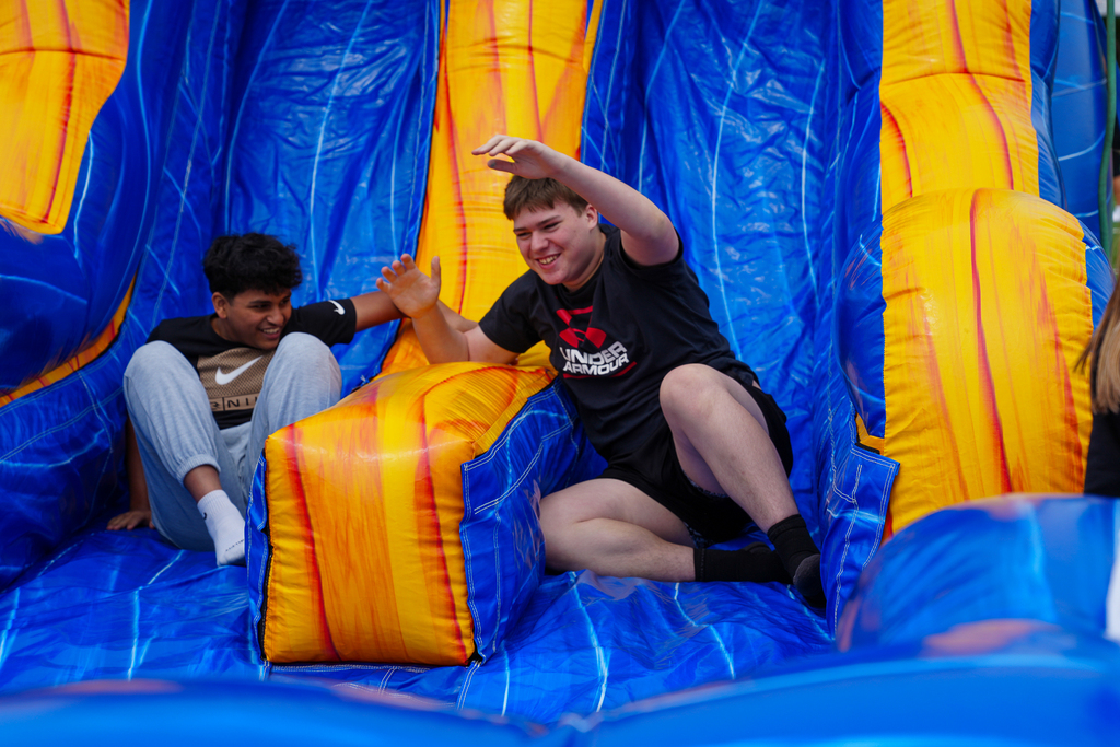 Two middle school students laugh as they make their way through an inflatable obstacle course during field day.