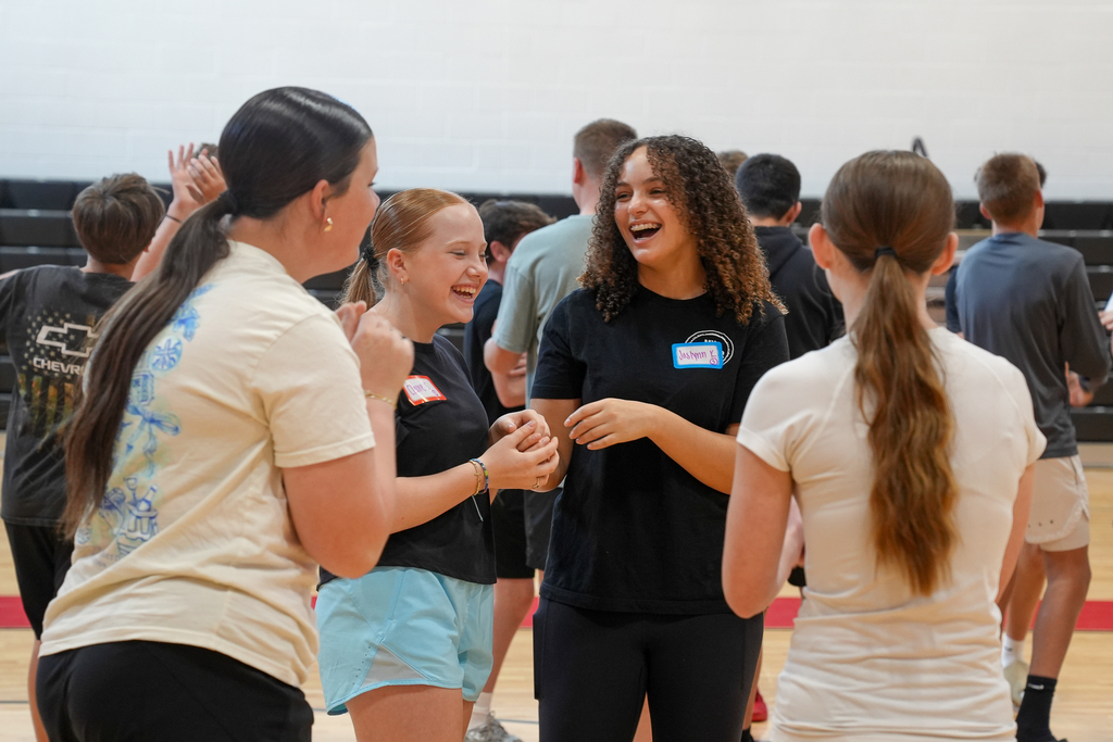 A group of students laugh and interact together during a WEB team-building activity designed to help prepare student leaders for welcoming incoming sixth graders.