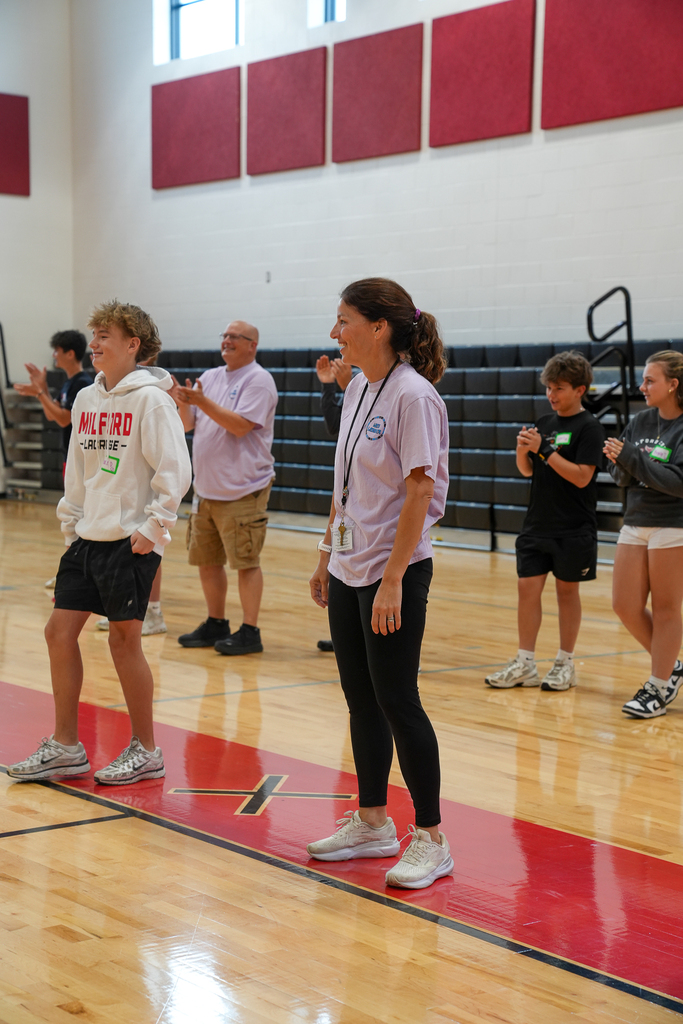 Students and staff members stand together applauding during a WEB training session focused on leadership and welcoming incoming sixth graders.