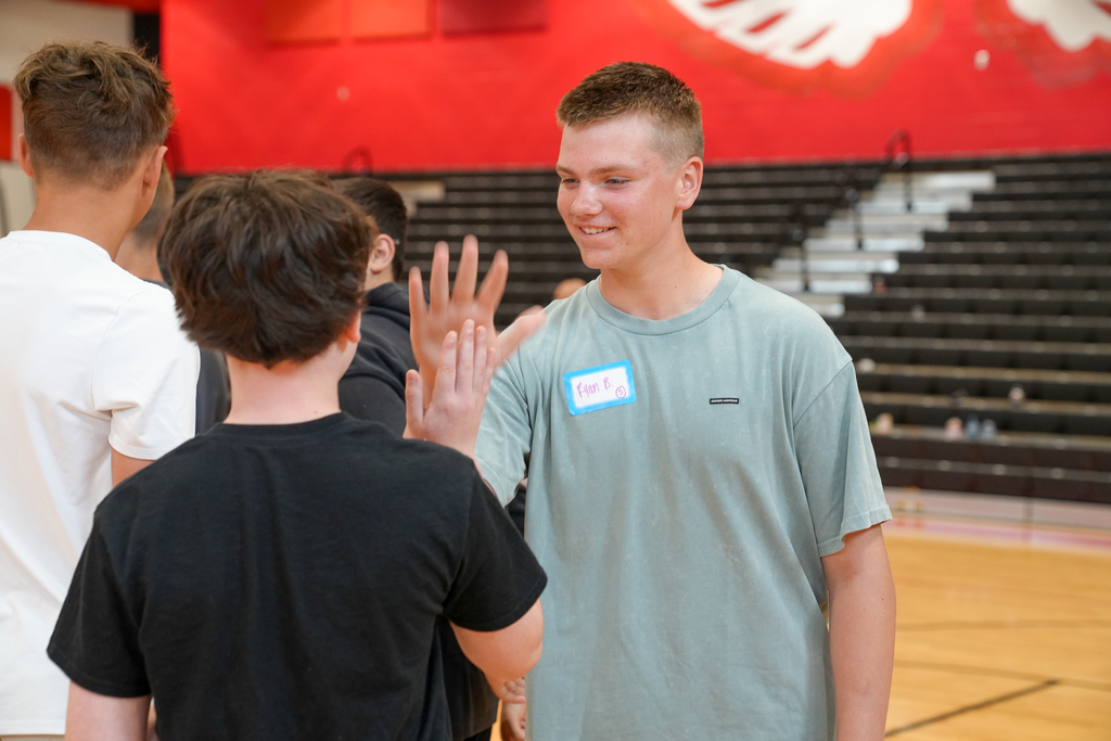 Two students smile while completing a partner activity during WEB leadership training in the Milford Middle School gymnasium.