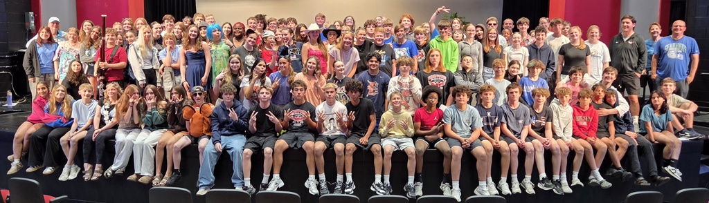 Large group photo of Milford Middle School students and staff gathered on the stage inside Milford High School’s Zamudio Theatre following the school talent show. Students wearing casual clothing and costumes smile and pose together across the stage, celebrating an afternoon of performances and entertainment.