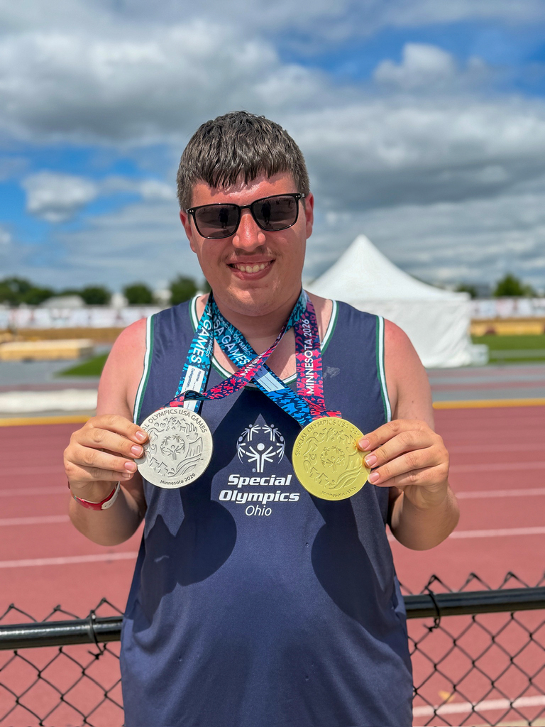 Jackson Witsken smiles while standing beside an outdoor track and holding the two medals he earned while representing Special Olympics Ohio at the 2026 Special Olympics USA Games.