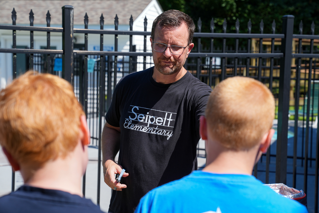 A Seipelt Elementary staff member speaks with two students near the school’s pool area.