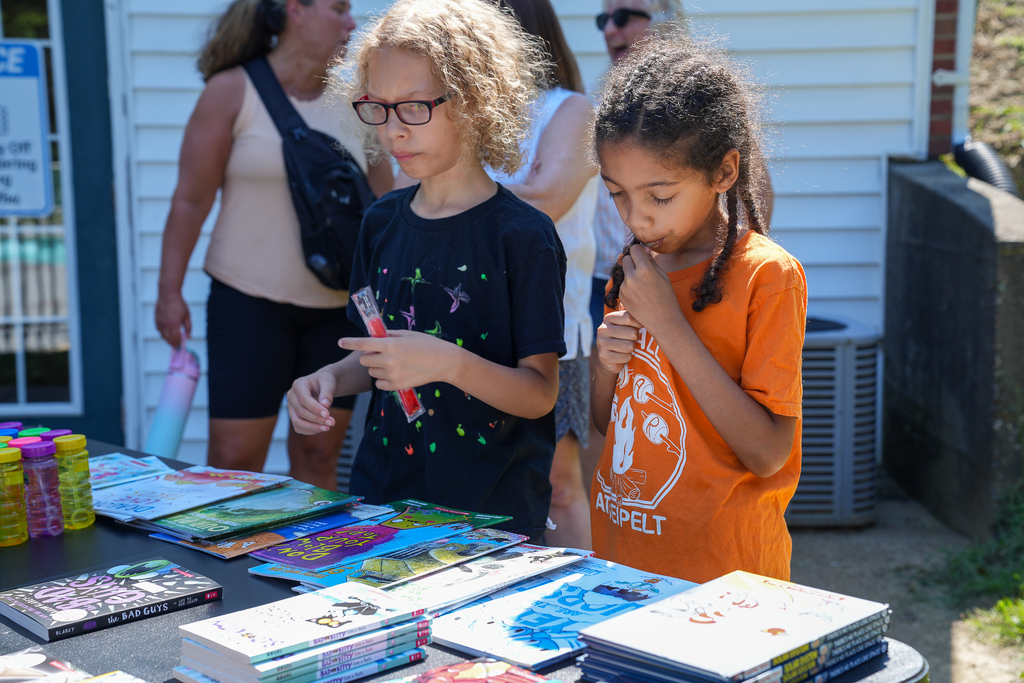 Two students browse books and enjoy frozen treats at an outdoor Seipelt Elementary event.