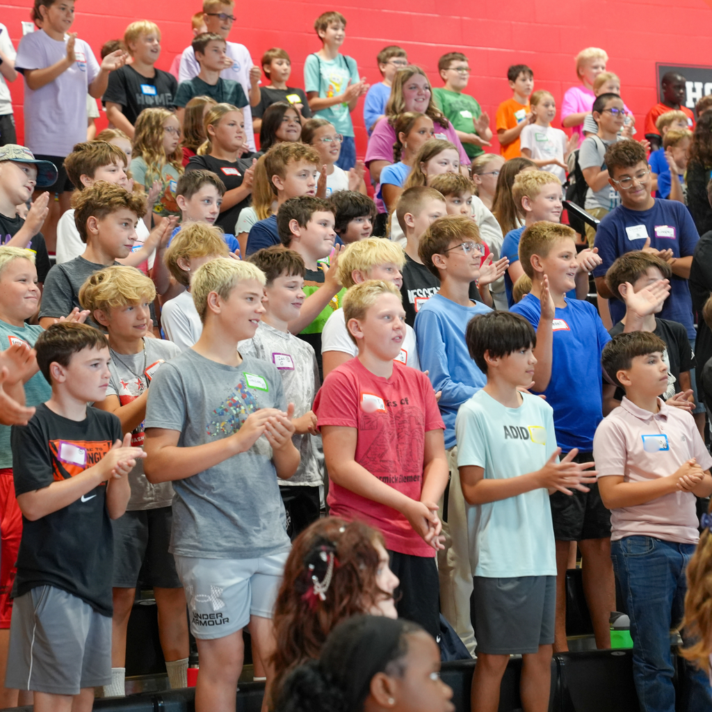 Incoming sixth-grade students stand together in the Milford Middle School gymnasium during a large-group WEB Orientation activity. Students clap and participate as WEB leaders guide the group through welcoming activities.