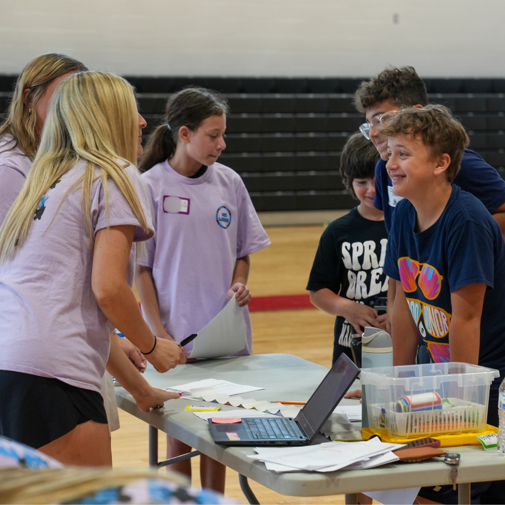 WEB leaders assist incoming sixth-grade students at a registration table during Milford Middle School WEB Orientation. Students check in, receive materials, and ask questions before participating in the day's activities.