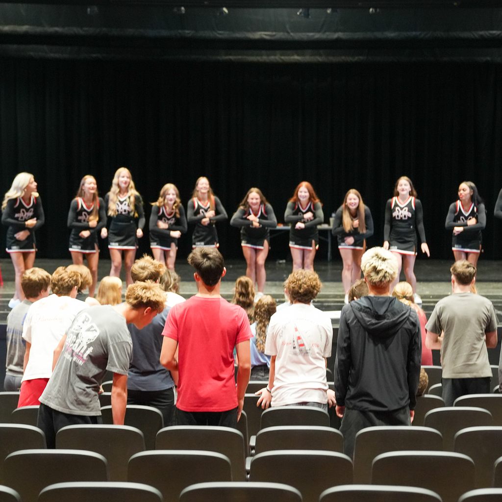 Milford High School cheerleaders perform on stage while incoming freshmen watch from the audience during Freshman Orientation, introducing students to school spirit and extracurricular opportunities.