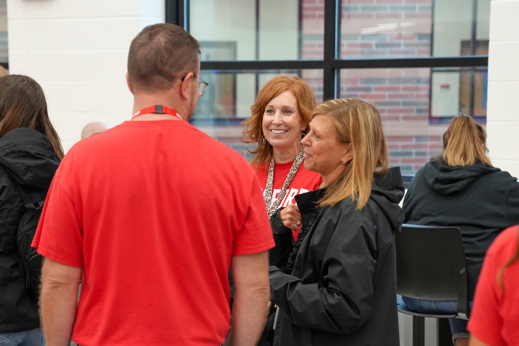 Three Milford staff members talk and smile together during the annual staff convocation.