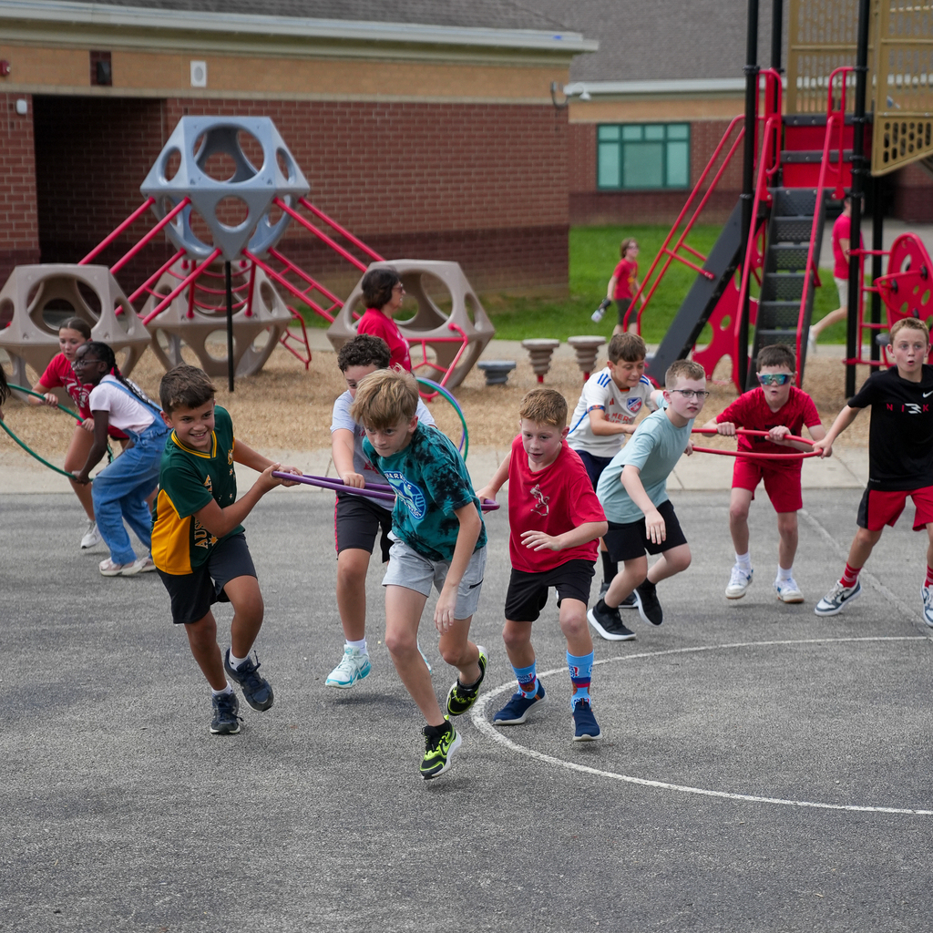 McCormick Elementary students race together while holding colorful hula hoops during an outdoor PBIS celebration.