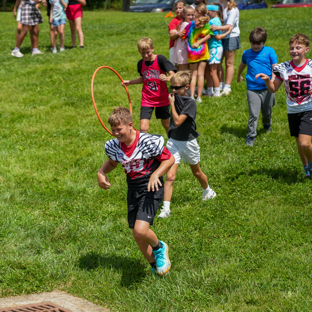 McCormick Elementary students run through a hula-hoop course on the grass during an outdoor PBIS celebration