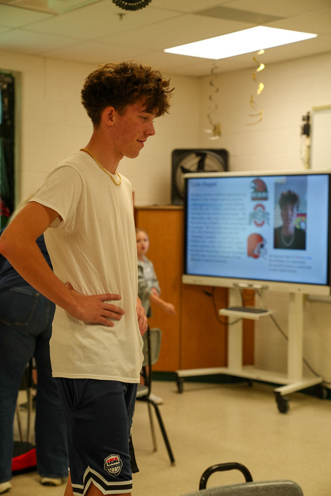 A Milford High School student mentor stands at the front of a Mulberry Elementary classroom giving a presentation to students.