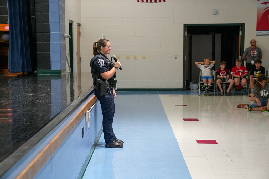 A uniformed police officer speaks to Meadowview students during the school assembly.