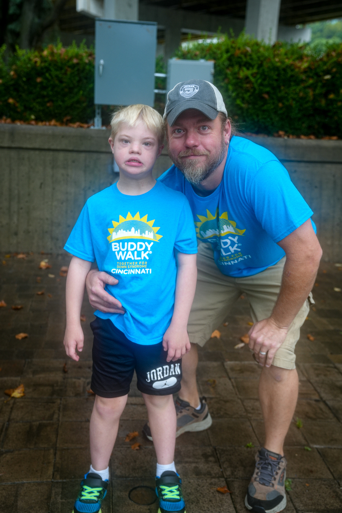 A child and an adult wearing matching blue Cincinnati Buddy Walk shirts pose together during the event.