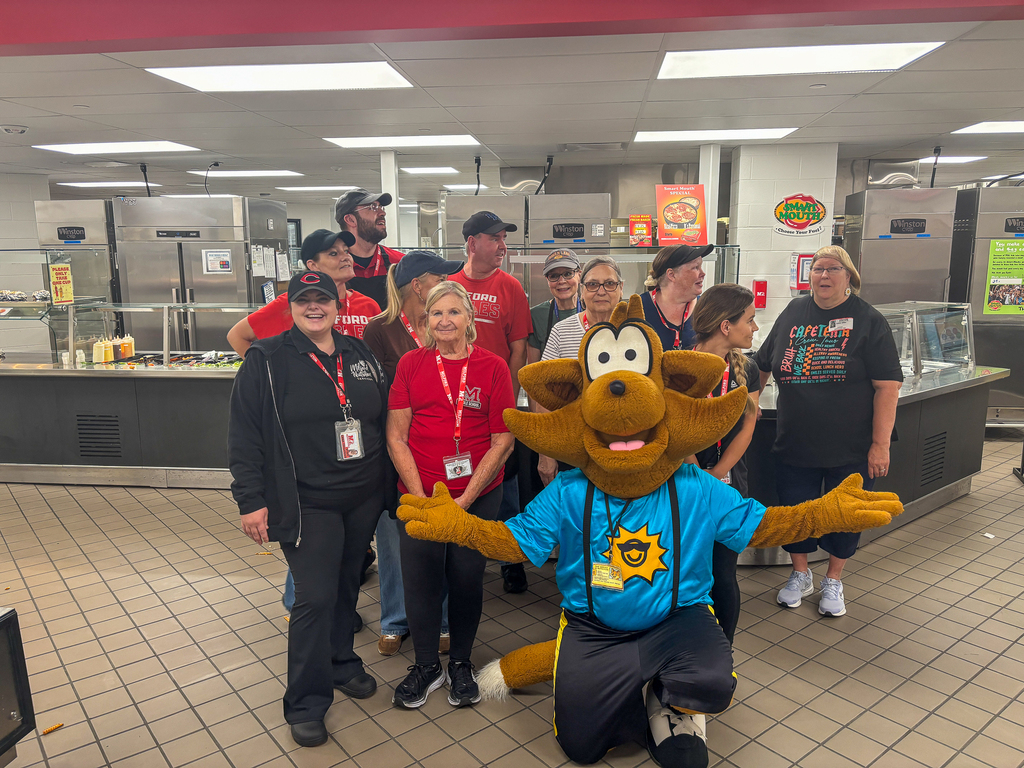 Munch the Fox poses with members of Milford’s School Nutrition staff in the cafeteria serving area.