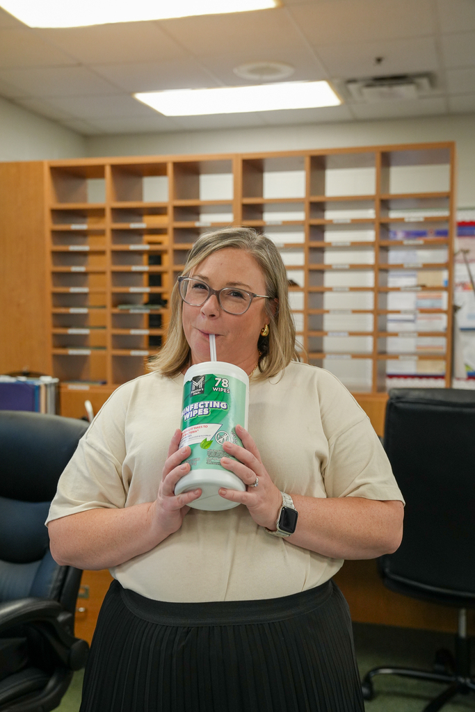 A staff member drinks through a straw from a repurposed disinfecting-wipes container.