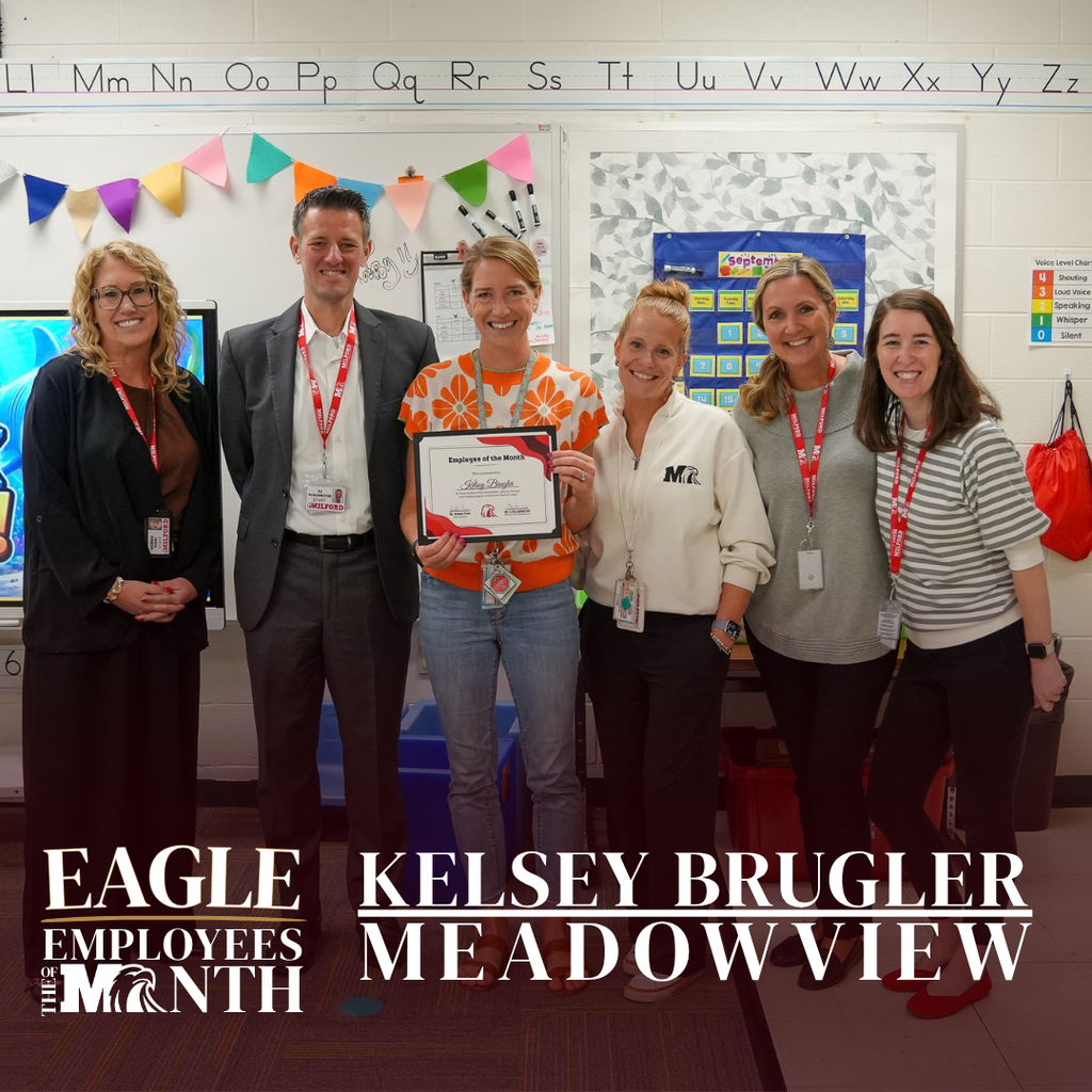 Eagle Employee of the Month Kelsey Brugler of Meadowview Elementary holds her award while posing with five colleagues in a classroom.