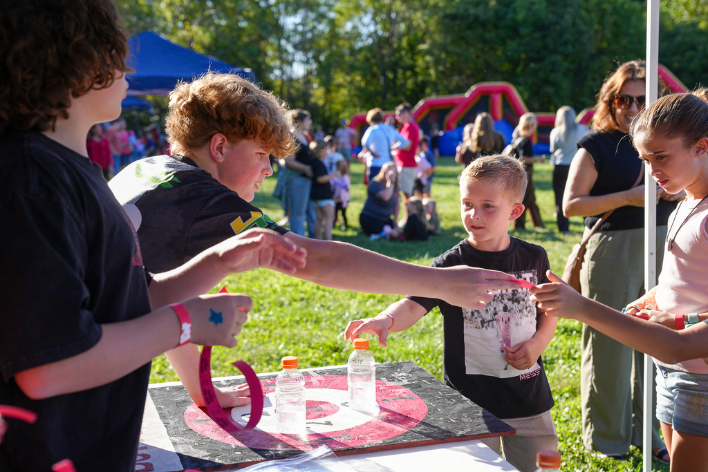 Students participate in a carnival-style game at McCormick Fest while families and other activities fill the school grounds behind them