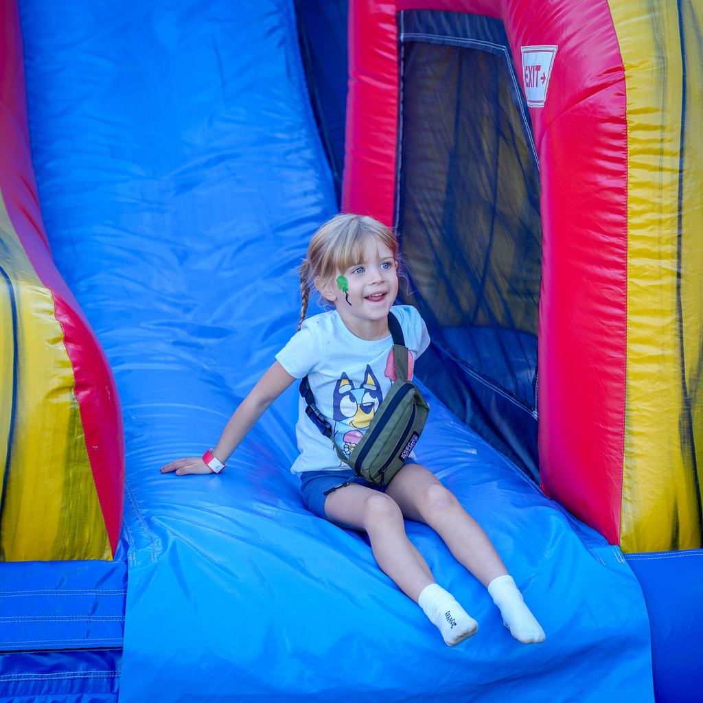 A young student smiles after coming down a colorful inflatable slide at McCormick Fest