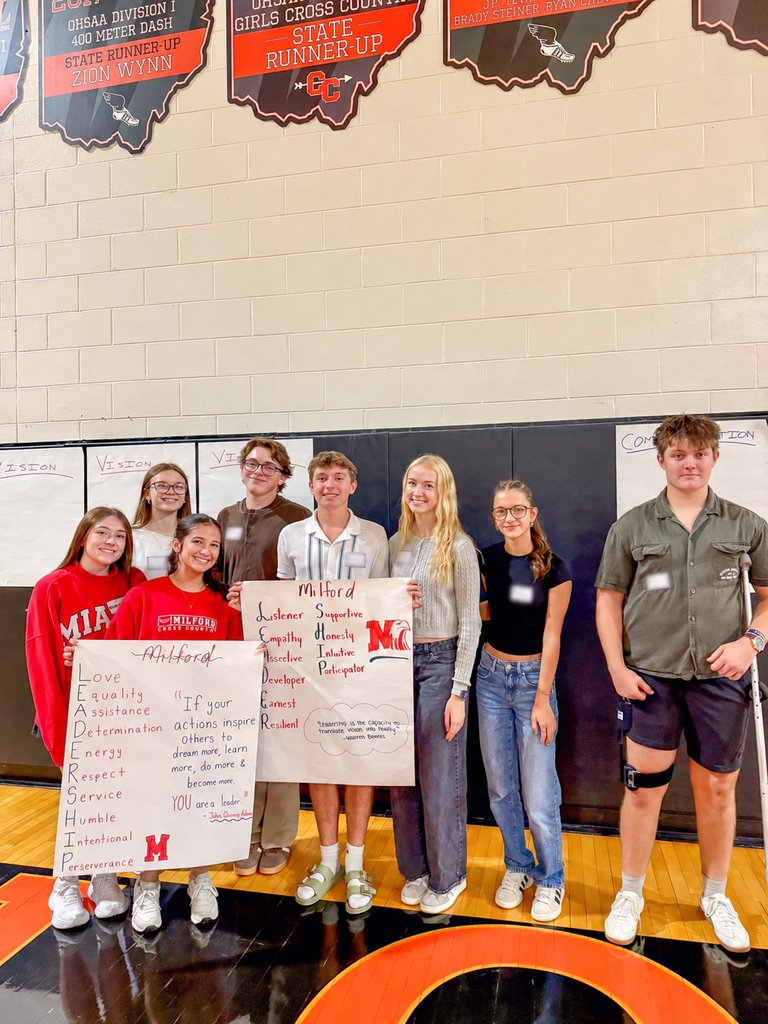 Eight Milford students pose with two handmade posters about leadership and service.