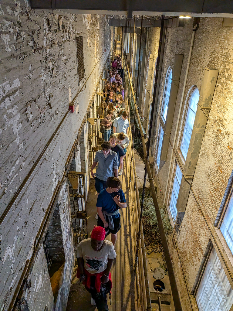 Milford theatre students walk along a narrow upper-level passage inside the Ohio State Reformatory.