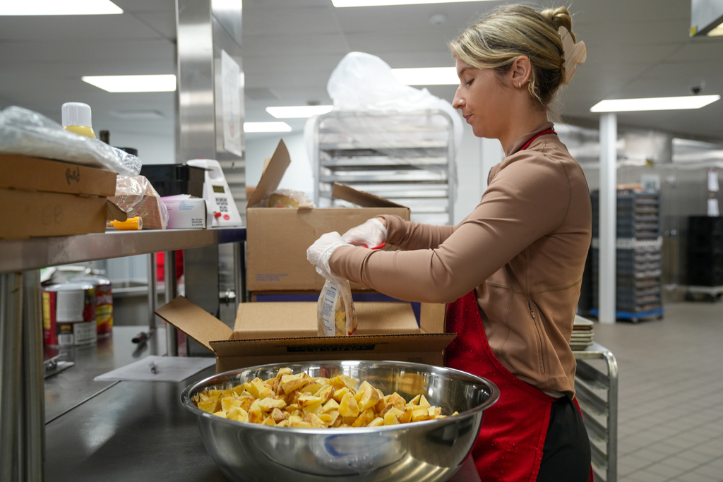 A woman seasoning a large bowl of potatoes