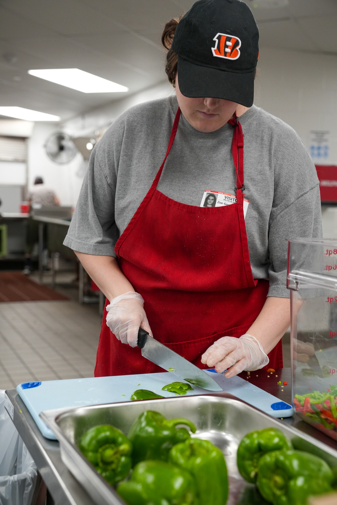 A School Nutrition staff member slices fresh green peppers while preparing food in the Milford Middle School kitchen.