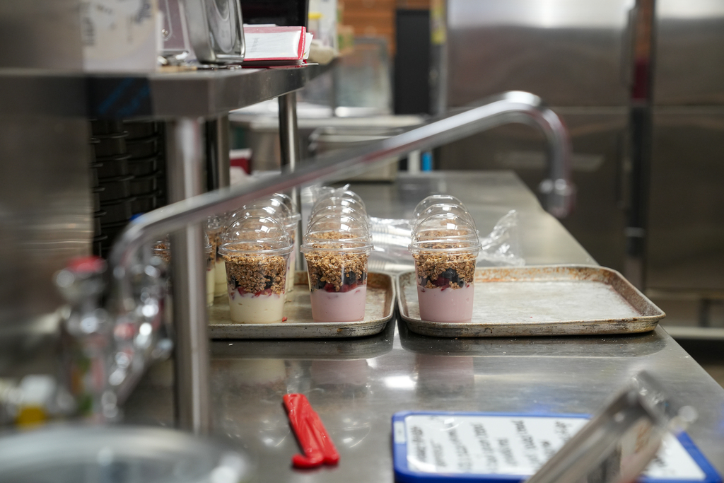Individual yogurt parfaits topped with fruit and granola sit on trays in the Milford Middle School kitchen. Alt text: A Milford