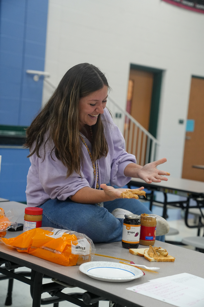 A McCormick Elementary staff member laughs while demonstrating how to make a peanut butter and jelly sandwich as part of a lesson on following step-by-step instructions.